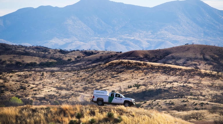 A U.S. Border Patrol agent parks near the border fence in...