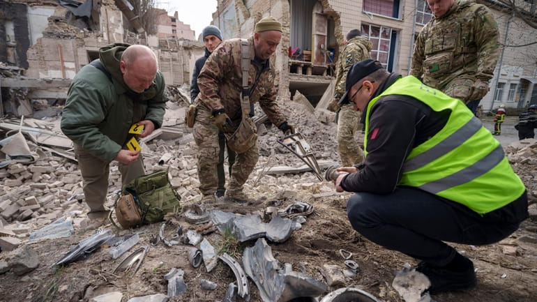 Ukrainian military experts gather remains of a missile next to...