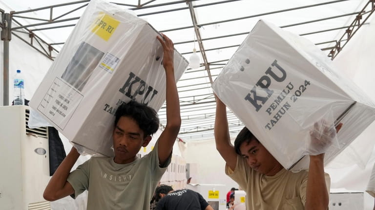 Workers carry ballot boxes to be distributed to sub-districts at...