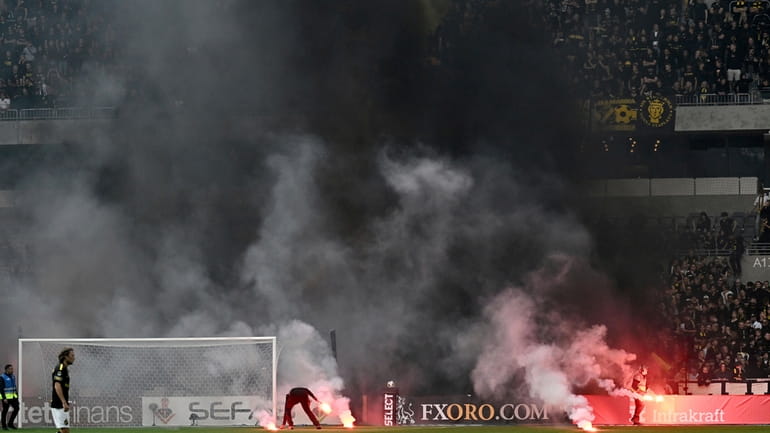 Flares are thrown on to the pitch by AIK supporters...