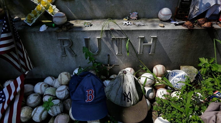 Items left by visitors decorate the grave of George Herman...