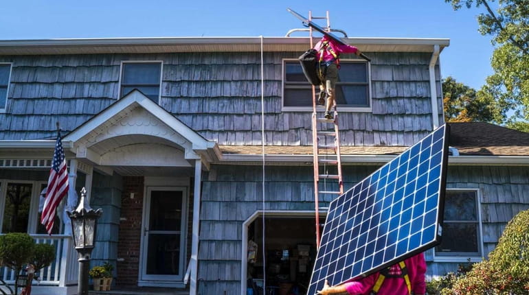 Employees of SunNation install solar panels at a residential home...