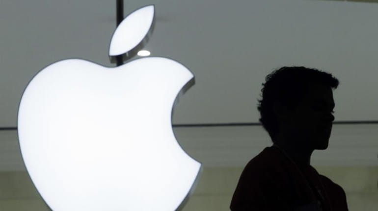 A person stands near the Apple logo at the company's...