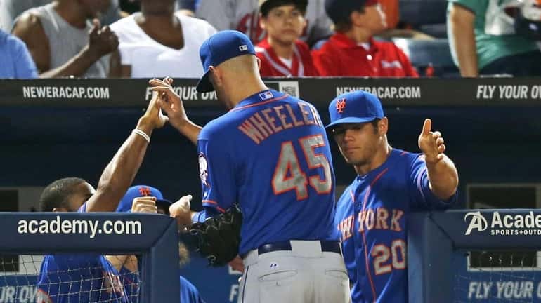 Mets starting pitcher Zack Wheeler is greeted at the dugout...