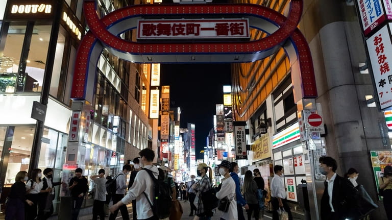 People walk under the main gate to Kabukicho, a night...
