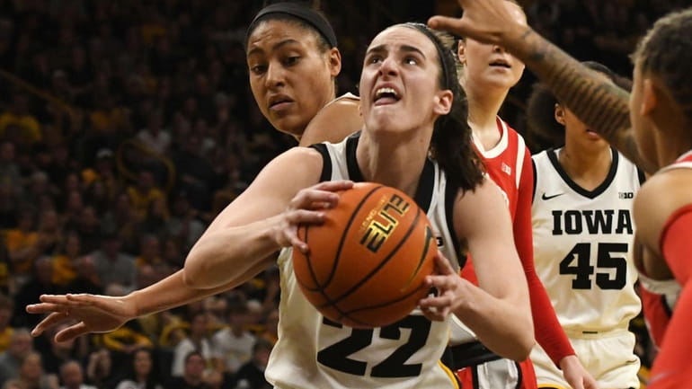 Iowa guard Caitlin Clark drives to the basket between Ohio State...