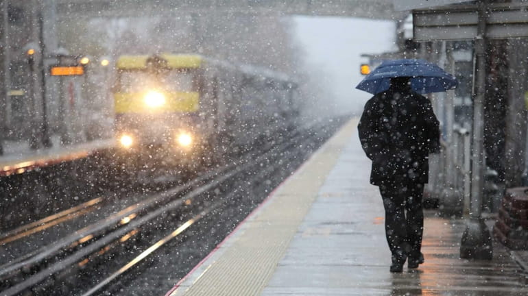 Commuters dodge snowflakes at the Mineola LIRR station in Mineola....