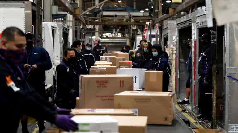 Employees sort packages at the FedEx regional hub at Los...