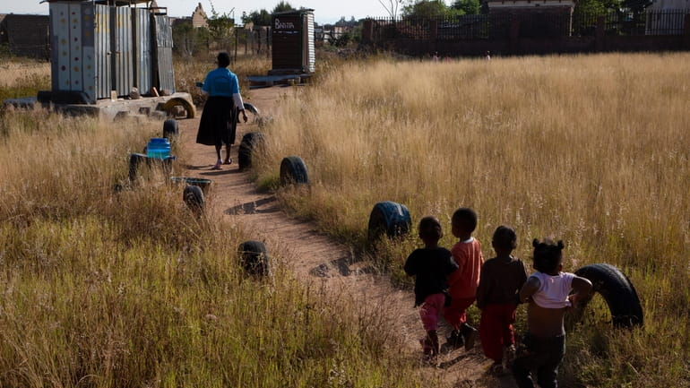 Children follow school manager, Florina Ledwaba, toward pit toilets at...