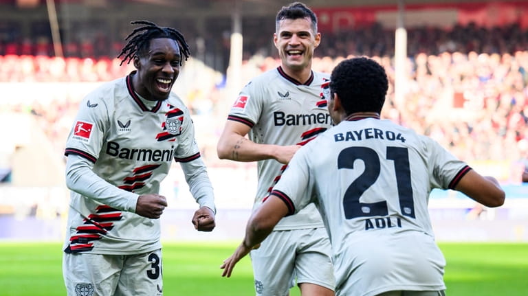 Leverkusen's Jeremie Frimpong, left, celebrates after scoring the opening goal...