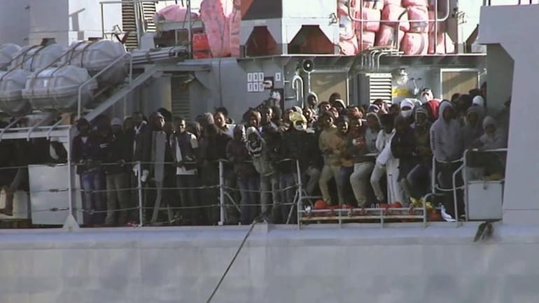 In this image from TV, migrants crowd at the rail...