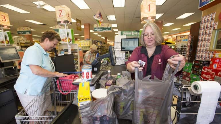 Susan Fisher, a cashier at the IGA in Southold helps...
