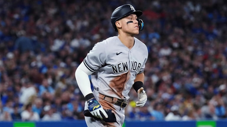 The Yankees' Aaron Judge jogs to first base after being...