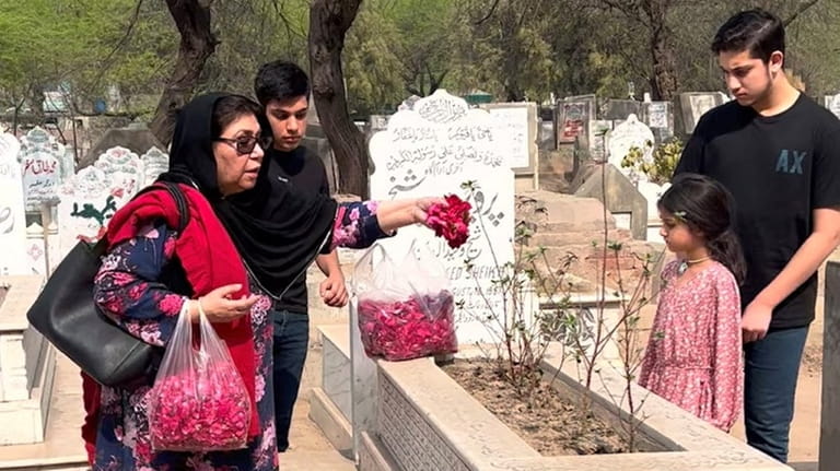 Wala Sheikh places flowers on the grave of her husband,...