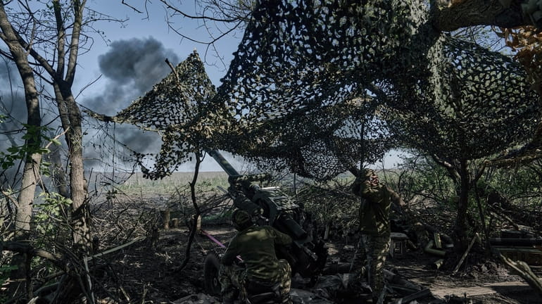 Ukrainian soldiers fire a cannon near Bakhmut, an eastern city...
