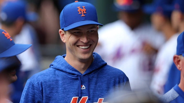 Mets starting pitcher Jacob deGrom smiles in the dugout before...