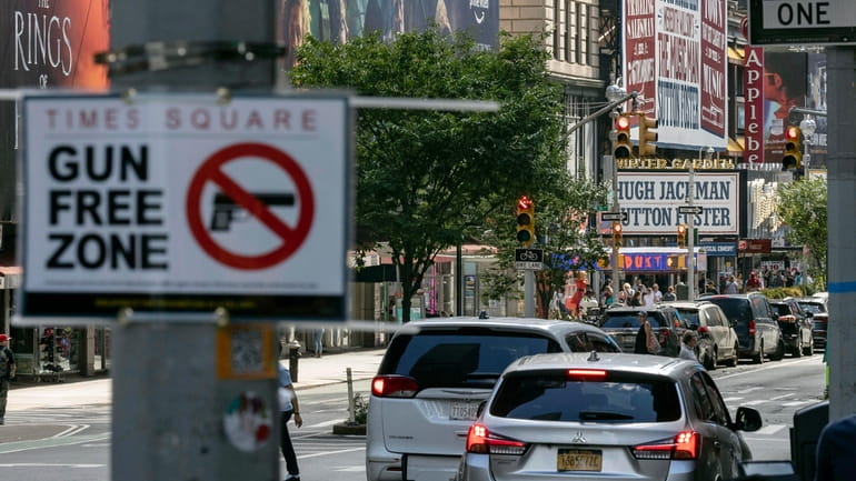 A sign reading "Gun Free Zone" is posted near Times Square,...