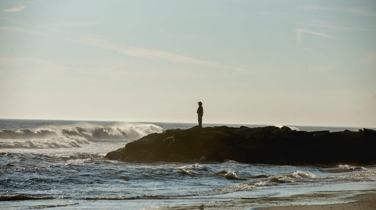 A beachgoer stands watch Thursday over the Atlantic Ocean off Long...