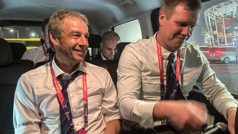 Juergen Klinsmann, left, sits in a car as he records...