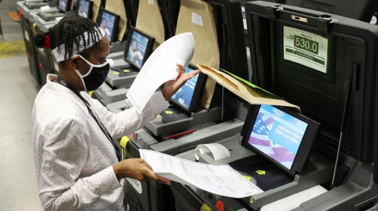 A Miami-Dade election worker feeds ballots into a voting machine during...