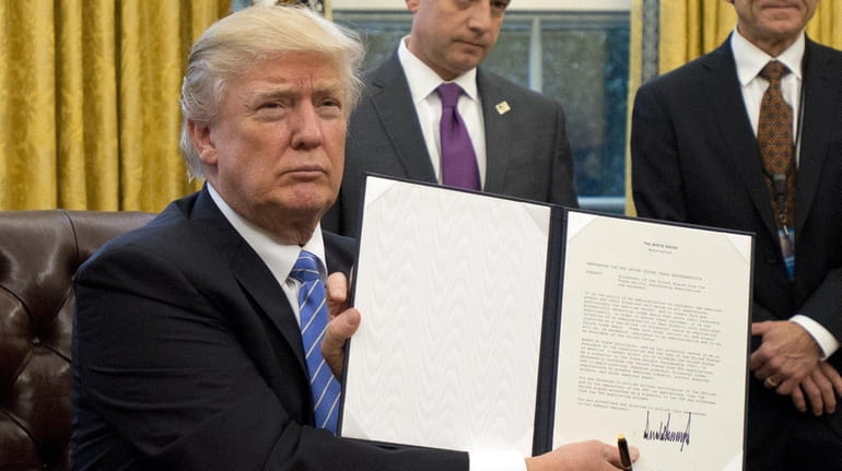 President Donald Trump shows the signed executive order withdrawing the...