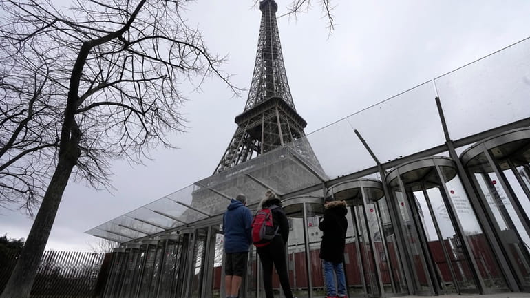 Visitors stand at the closed gates leading to the Eiffel...