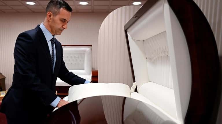 Brueggemann Funeral Home funeral director Craig DeMaio adjusts a casket in...
