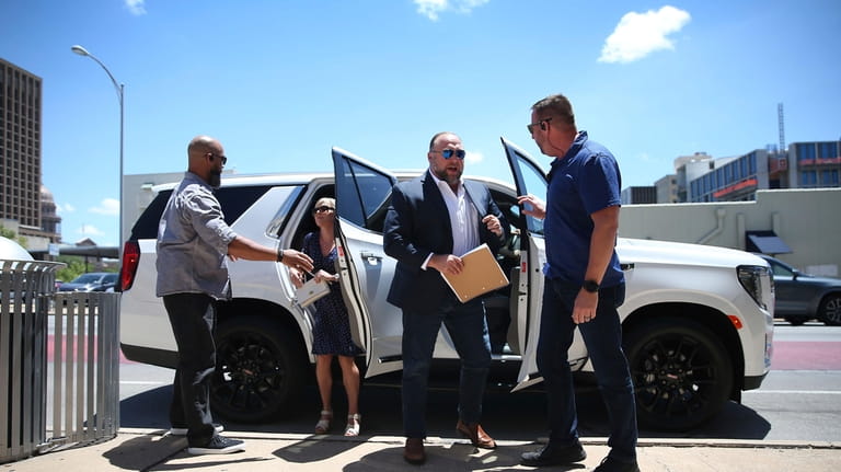 Alex Jones, second from right, arrives at the Travis County...