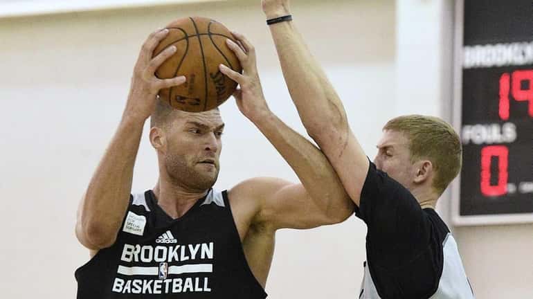 Nets center Brook Lopez is defended by forward Mason Plumlee...
