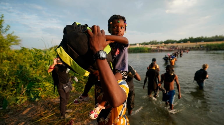 Migrants, many from Haiti, cross the Rio Grande from Del...
