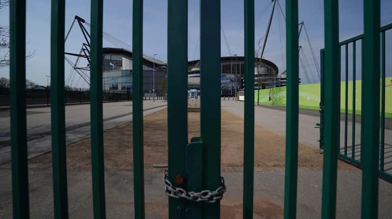 Gates stand locked outside the closed Manchester City Etihad Stadium in...
