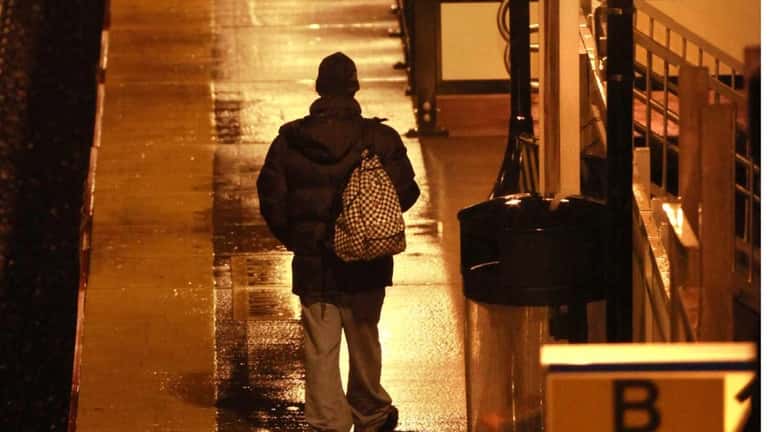 A commuter makes his way down the rain-soaked platform at...