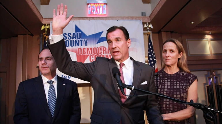 With his wife Helene at his side, Thomas Suozzi waves...