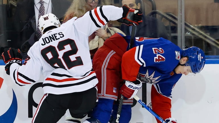Chicago defenseman Caleb Jones  fights for the puck against Rangers...
