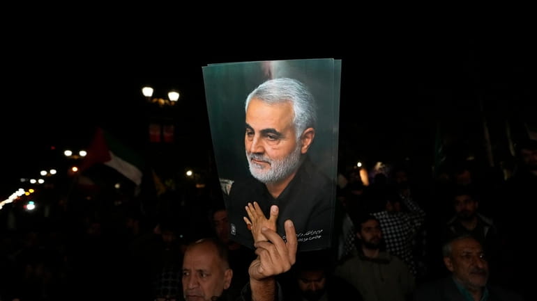 A demonstrator holds up a poster of the late Iranian...