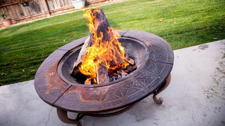 A portable fire pit burning in a backyard 