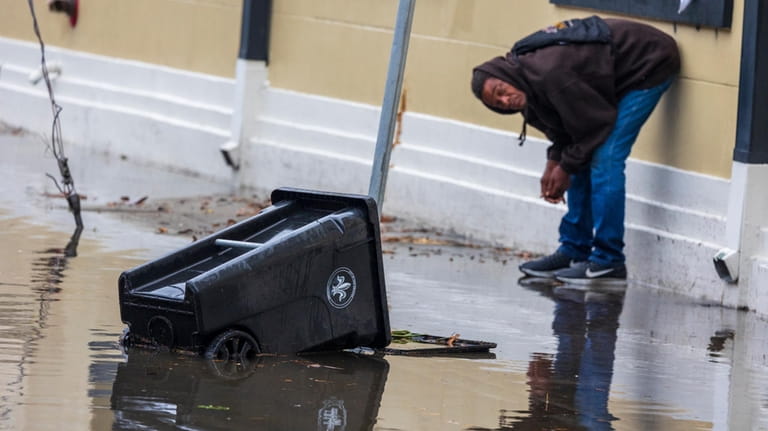 A person looks at a floating trash can as streets...