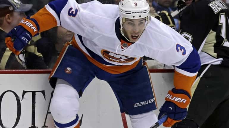 Travis Hamonic (3) is checked into the boards by Pittsburgh...