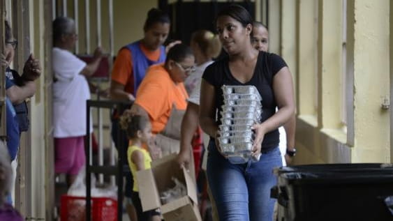 A woman passes out trays of food to evacuees at...