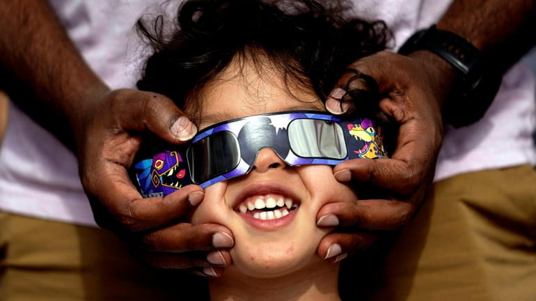 Viewers use special glasses to watch from San Antonio as the...