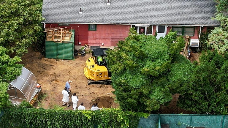 Police and crime scene investigators dig in the backyard of...