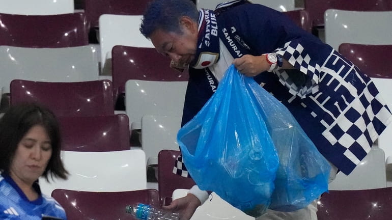 Japan supporters clean the stands at the end of the...