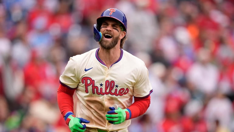 Philadelphia Phillies' Bryce Harper reacts after hitting an RBI-sacrifice flay...