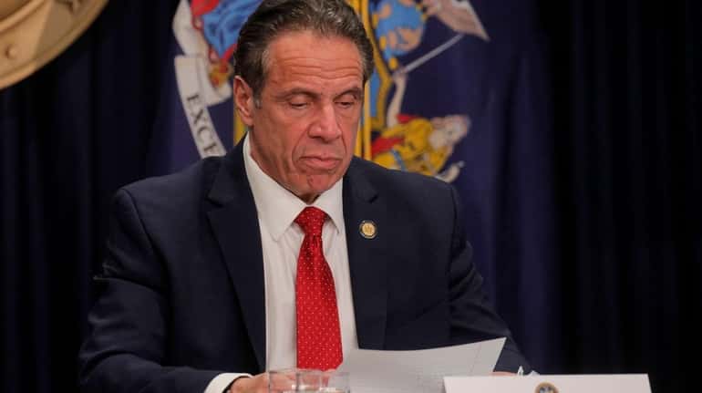 Gov. Andrew Cuomo reads a note as he speaks during...