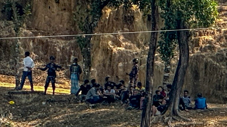 Members of Myanmar Border Guard Police, in civilian clothing, sit...
