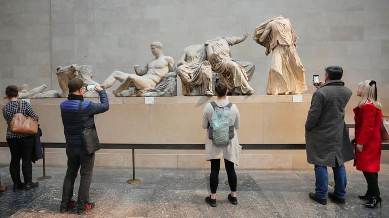 Visitors look at ancient sculptures that are part of the...