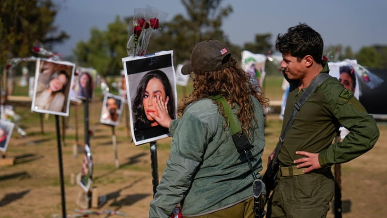 Israeli soldiers look at photos of people killed and taken...