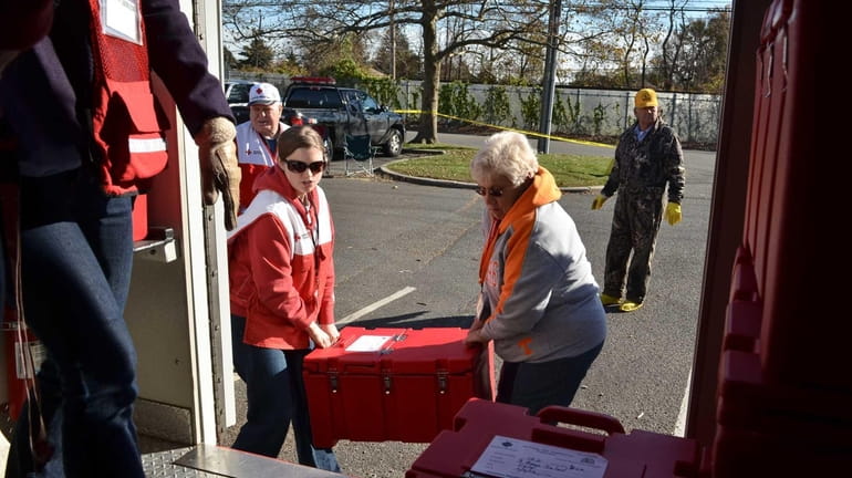 Volunteers with the American Red Cross load containers of hot...