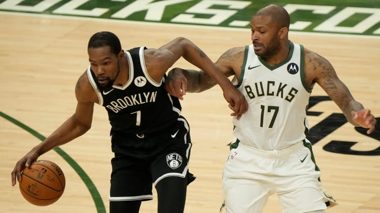 The Nets' Kevin Durant tries to drive past the Bucks'...