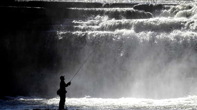 An angler fly fishes during in the afternoon at Taughannock...